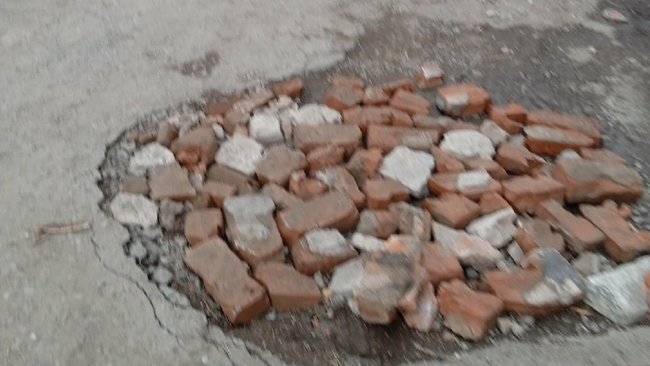 В Бузулуке дыры в асфальте засыпали кирпичами